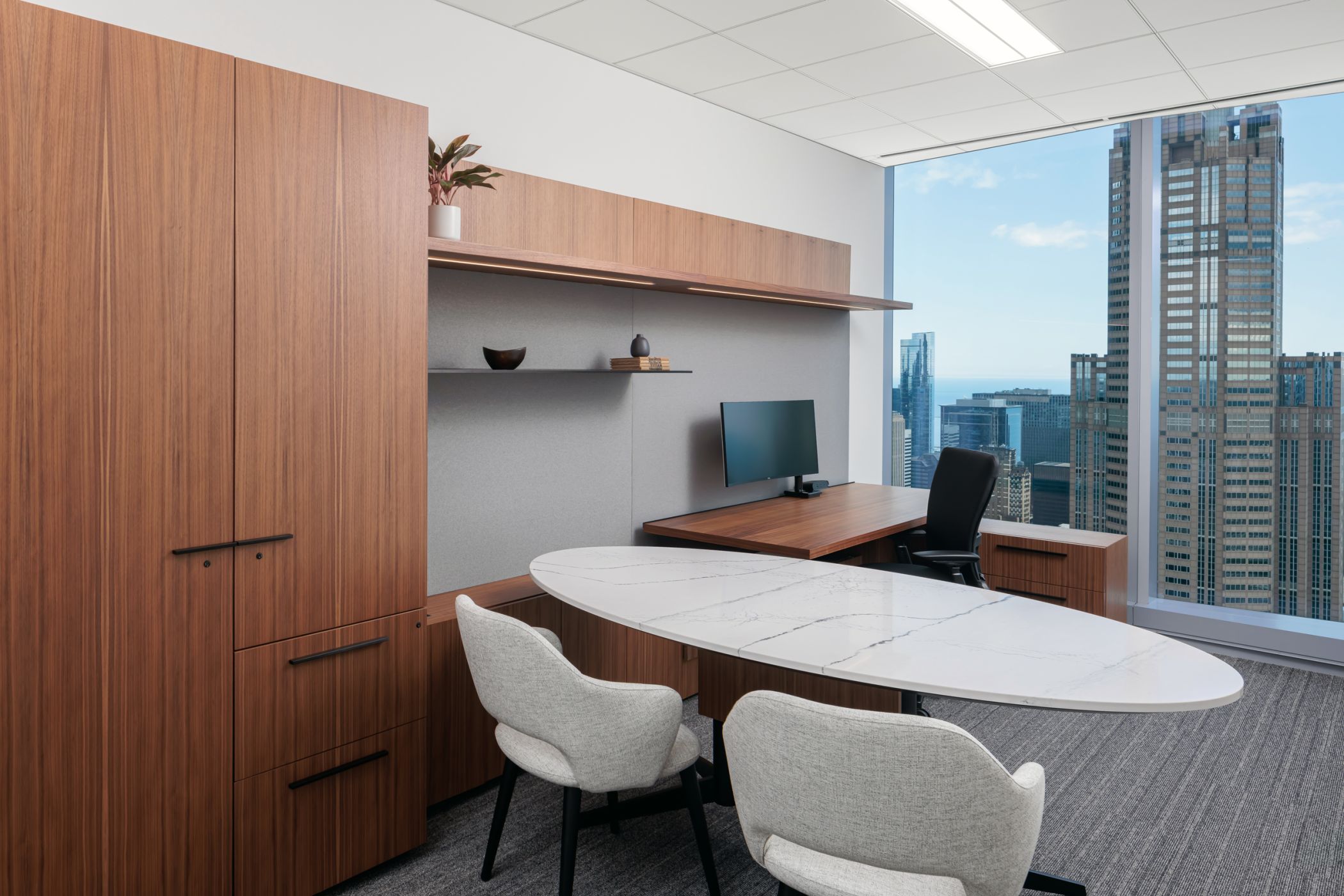 Custom Private office in book-matched, quarter-cut walnut with an elliptical SESSIONS table with black anodized base and Cambria worksurface.